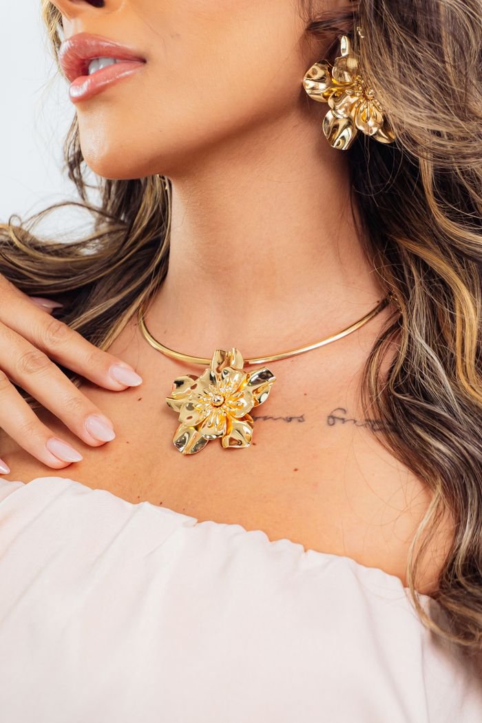Close-up of a woman with elegant gold necklace and earrings, exuding luxury and style.